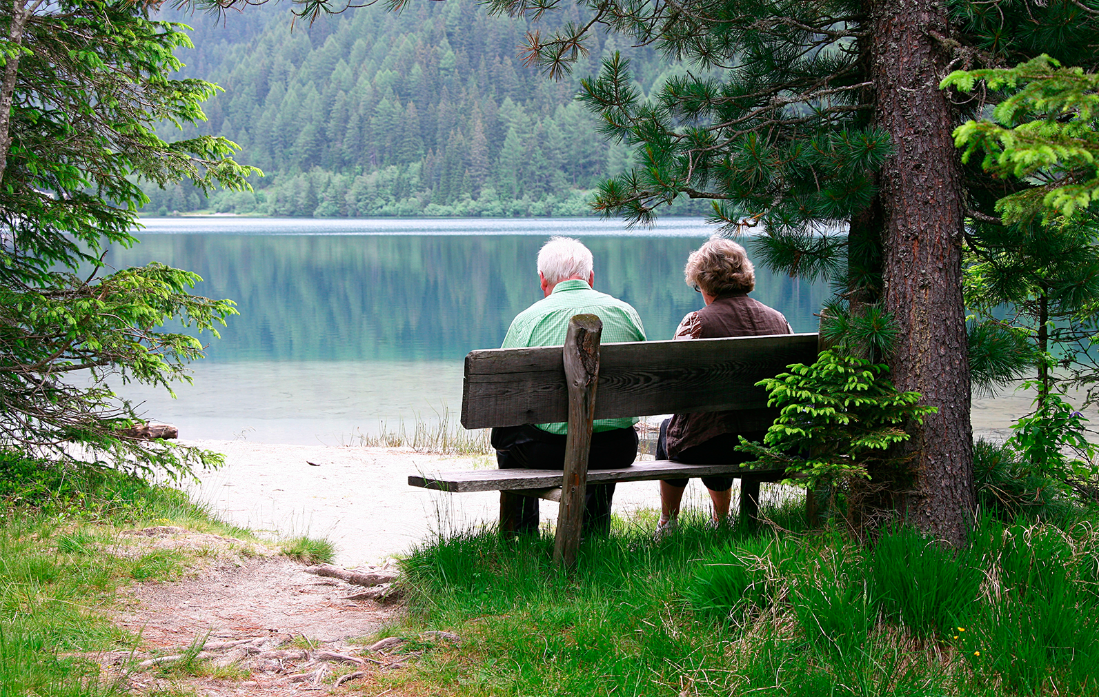 Pareja de ancianos sentados en un banco frente a un lago