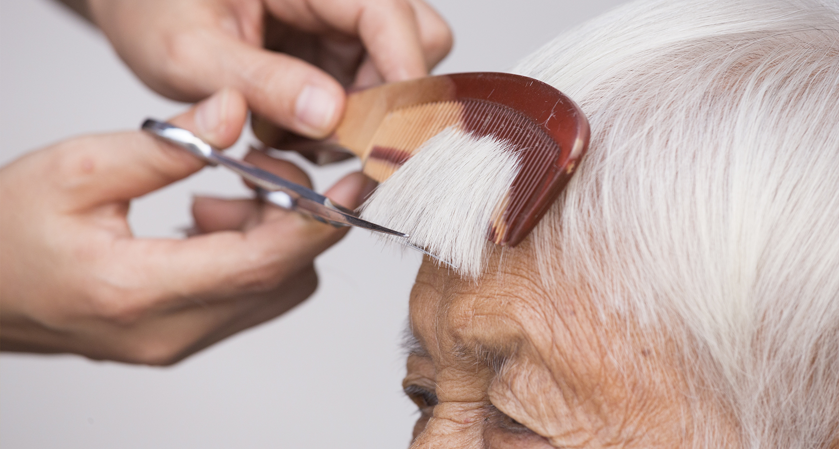 Tijera cortando el flequillo a una anciana
